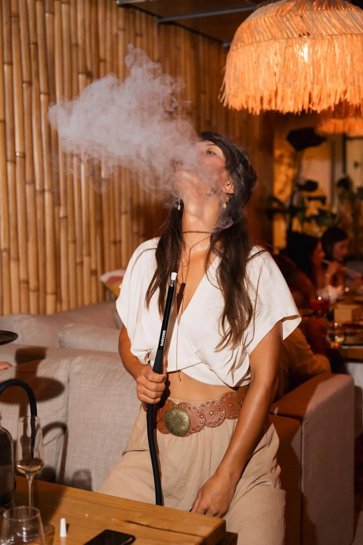 Guest exhaling shisha smoke at a Komodo Lounge table