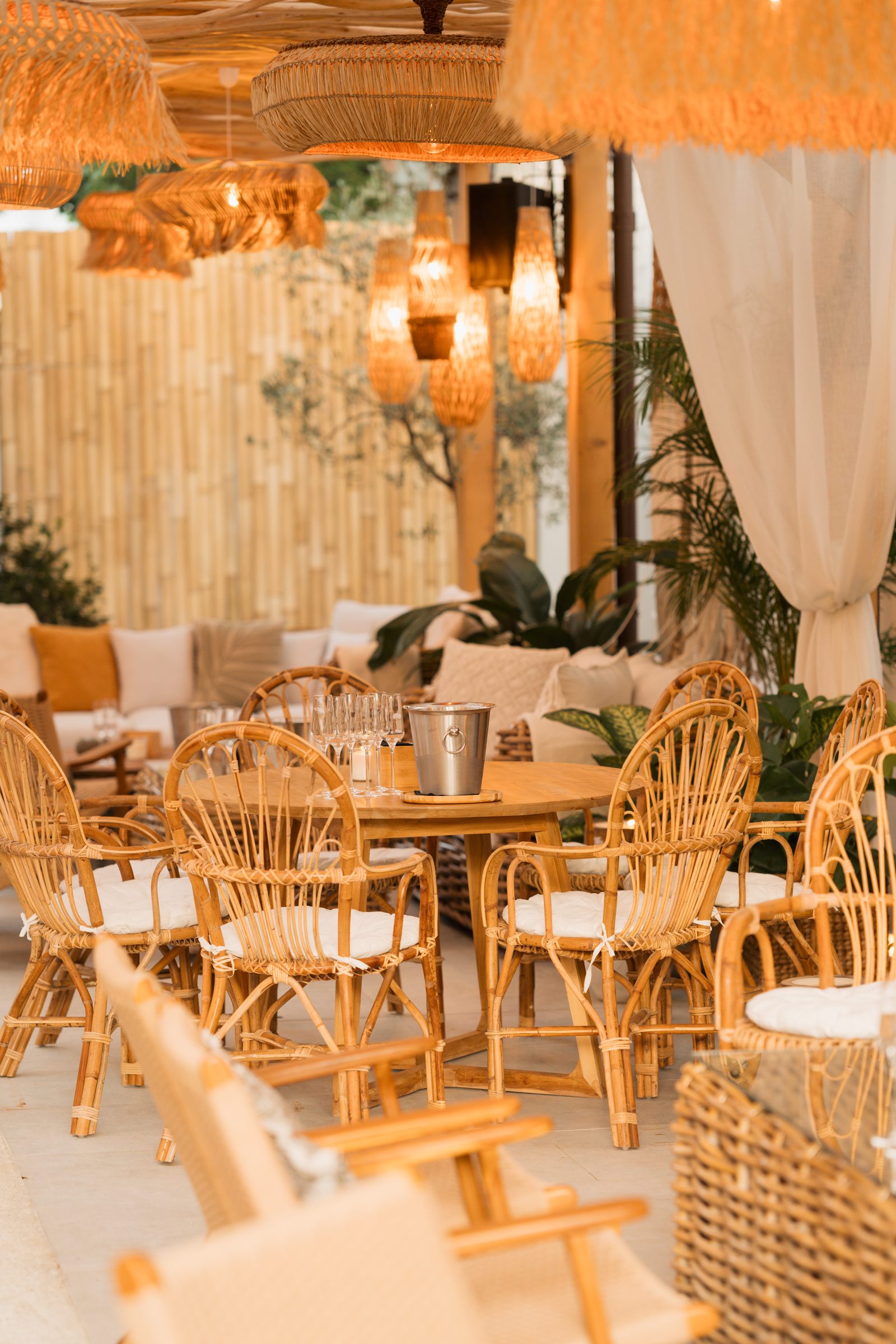 Komodo Lounge terrace dressed for the evening — rattan chairs around a wooden table with a champagne bucket