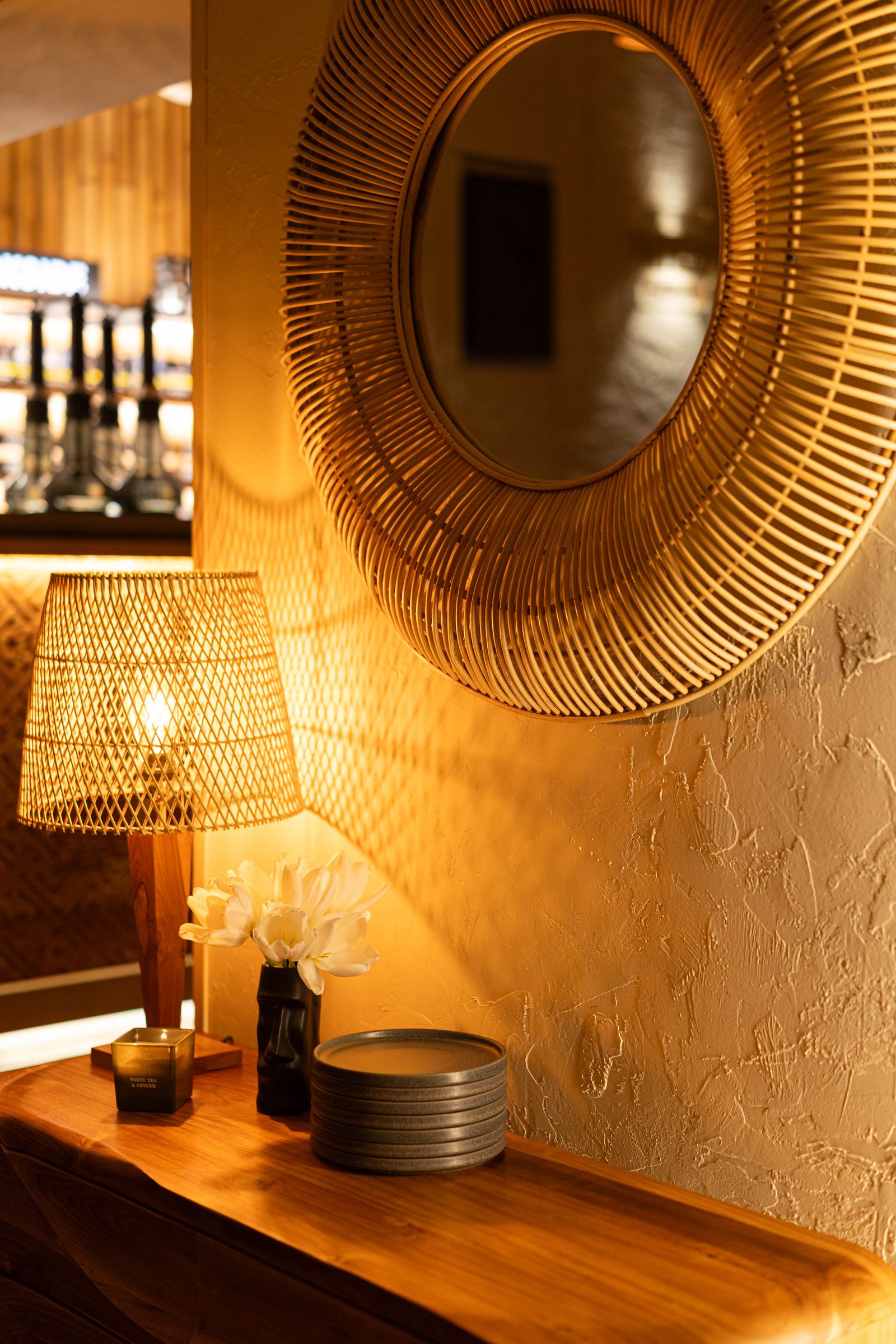 Warm interior detail with rattan mirror and lamp