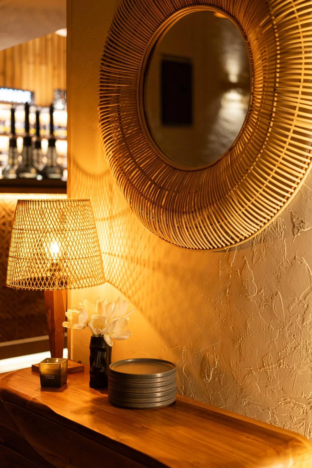 Warm interior detail with rattan mirror and lamp